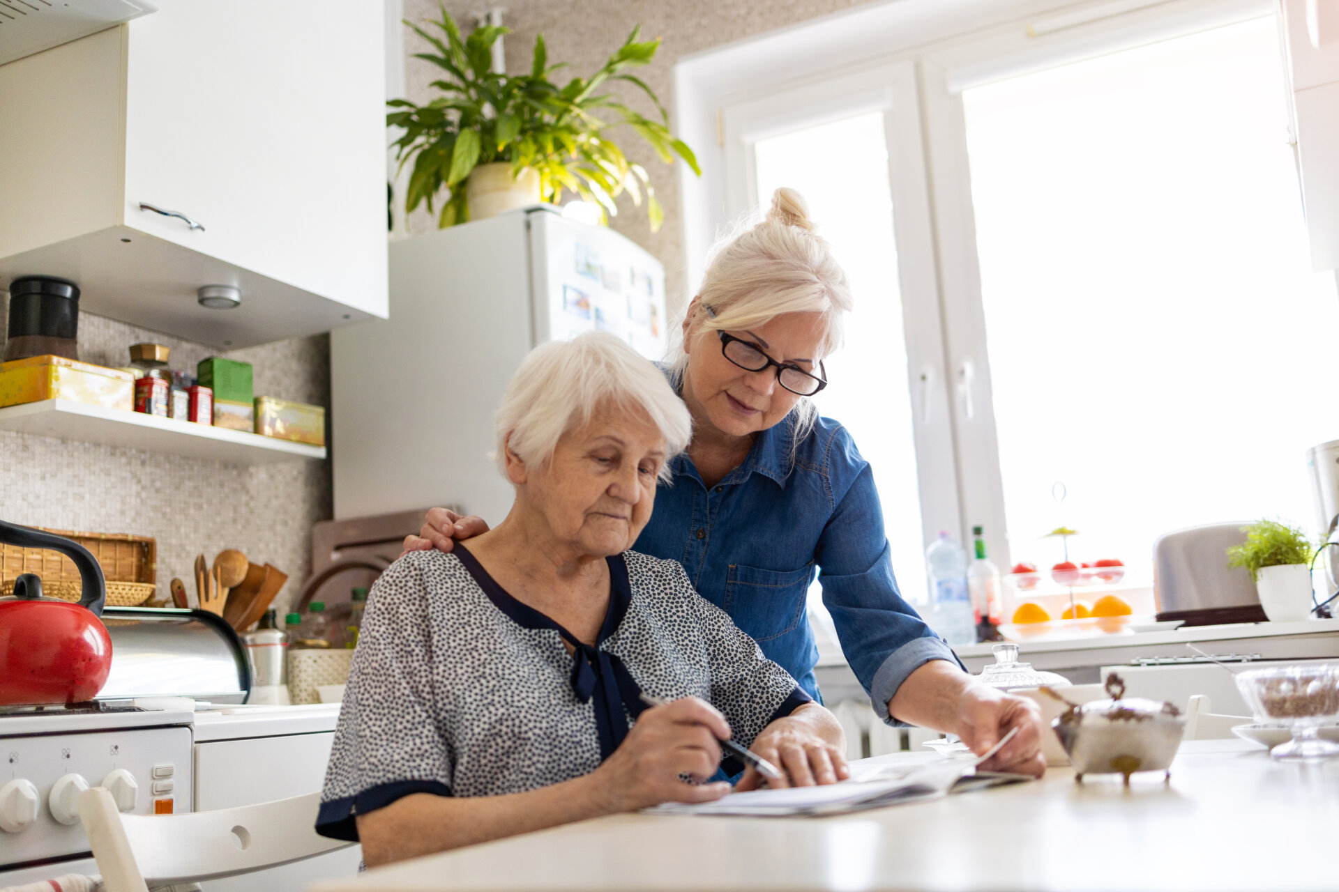 Mature woman helping elderly mother with paperwork