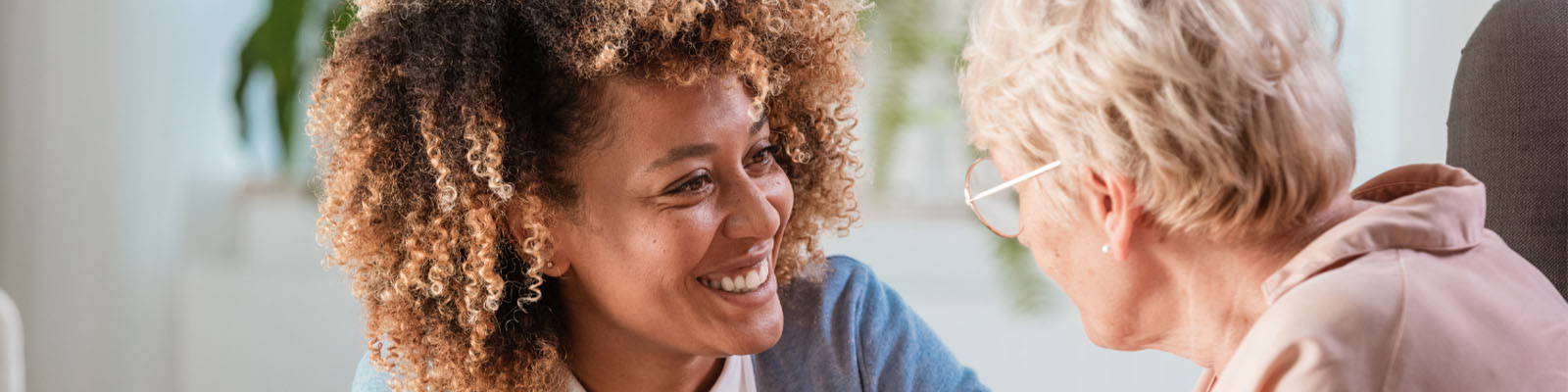 A senior woman sitting and talking with her nursing assistant